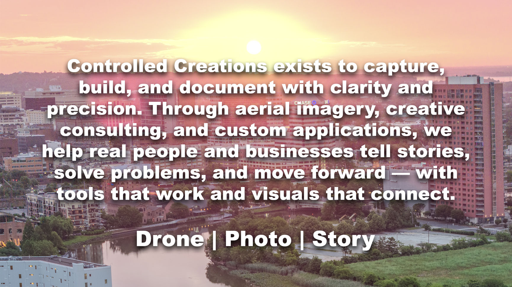 Wide-angle drone photo of sunrise over Wilmington, Delaware on the summer solstice, with warm orange skies and city skyline in the distance.