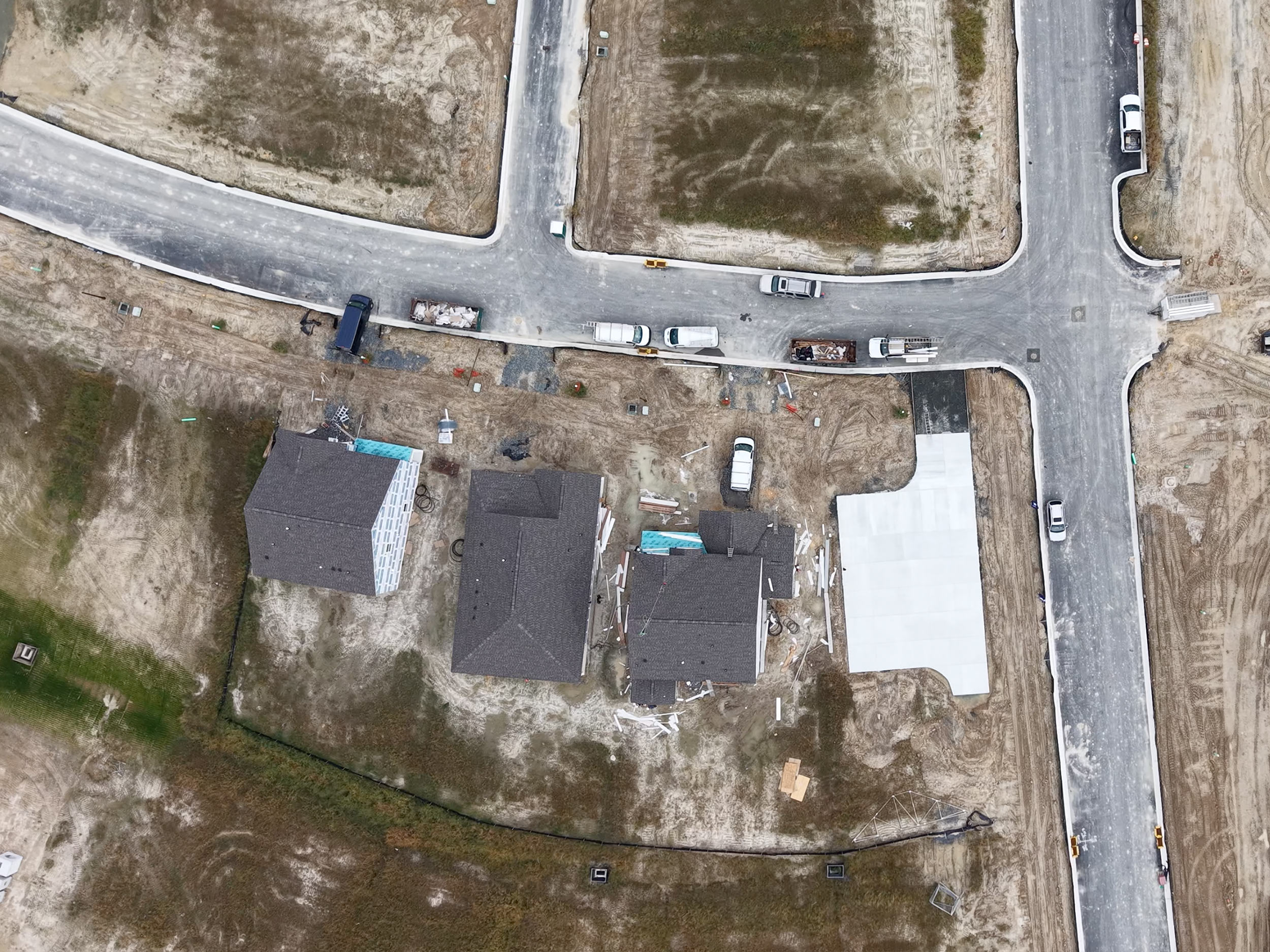 Top-down drone photo showing construction site layout, roads, and active home builds