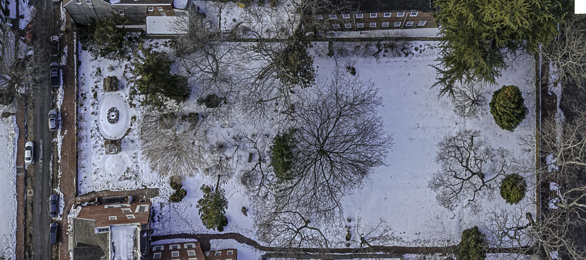 Top-down vertical aerial of Read House and Gardens showing full property footprint, existing trees, garden layout, street access, and neighboring properties under snow cover before restoration