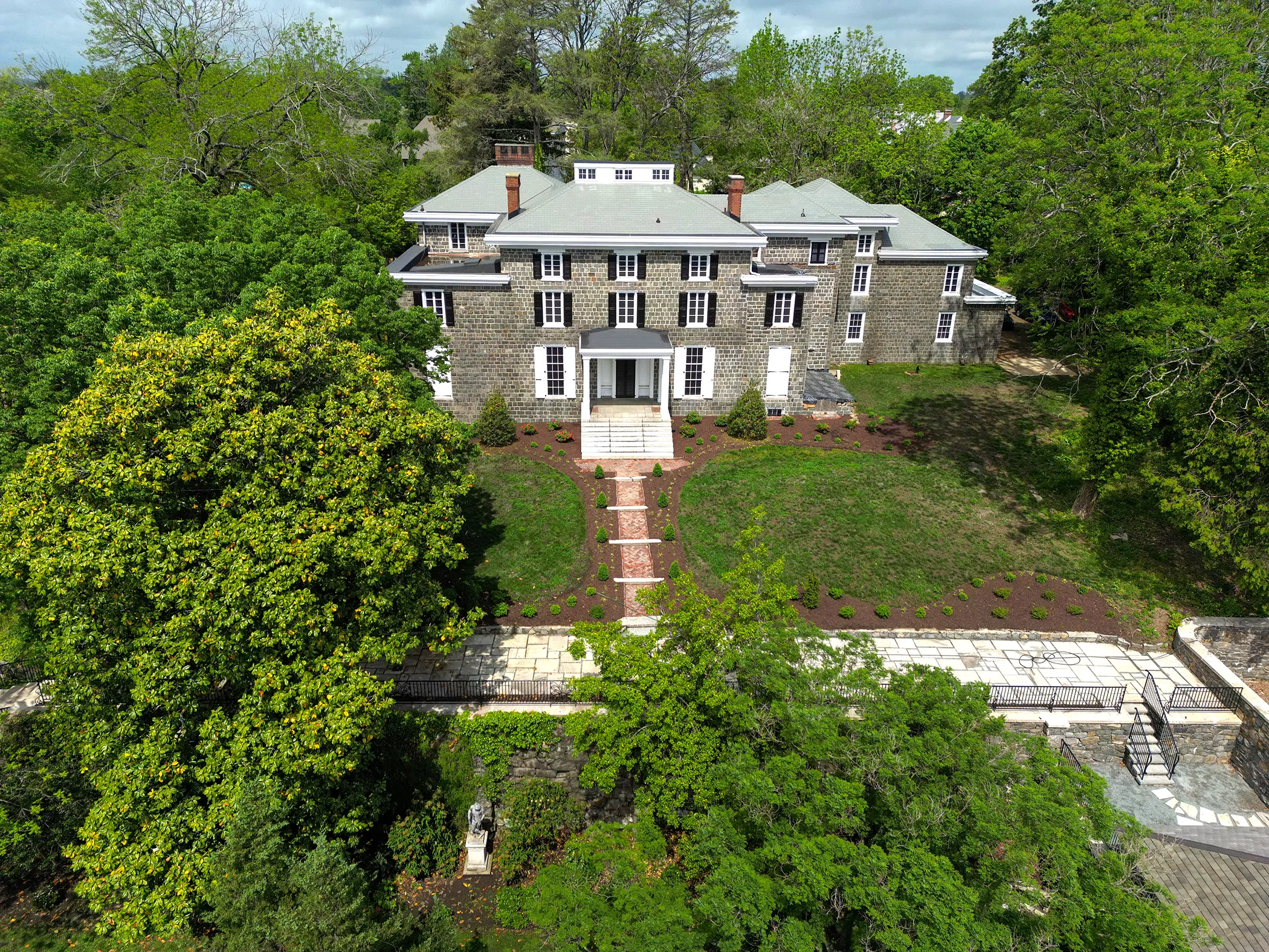 Aerial view of restored Gibraltar Estate mansion and grounds in spring 2025 showing fresh plantings, brick entry approach, marble promenade, and cleared landscape following restoration by Eastern Horticultural Services